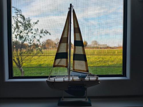 a small sail boat sitting in a window at vakantiehuisje DE WEELEN met Jacuzzi Huwelijks topkeuze! in Lutjebroek