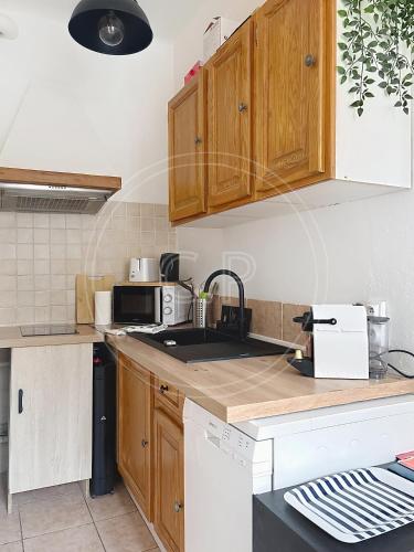 La cuisine est équipée de placards en bois, d'un évier et d'un four micro-ondes. dans l'établissement EDEN PLACE un petit coin de Paradis by LaConciergerie13, à La Ciotat