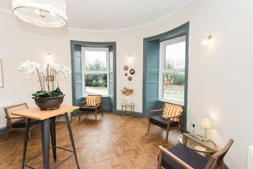 a living room with a table and chairs and windows at Torr House Hotel in Dumfries