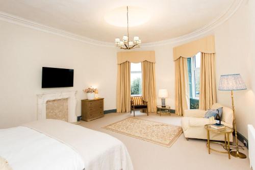 a white bedroom with a bed and a fireplace at Torr House Hotel in Dumfries