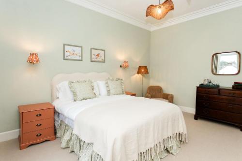 a bedroom with a white bed and a dresser and a mirror at Torr House Hotel in Dumfries