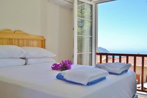 Una cama blanca con dos almohadas y flores moradas encima. en Villa Zeytin Kalkan, en Kas