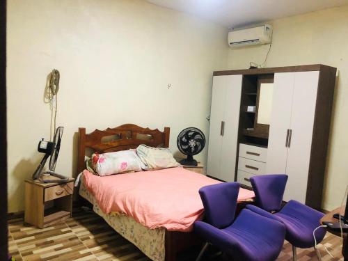 1 dormitorio con sillas moradas y 1 cama en Casa COP 30 PRAIA- Avenida ourém, Bairro Murubira nº5, en Mosqueiro