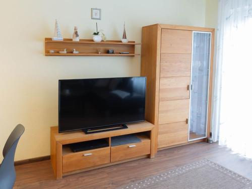 a flat screen tv sitting on a wooden entertainment center at Ferienhaus Marisol, FeWo Vermittlung Nordsee in Dangast