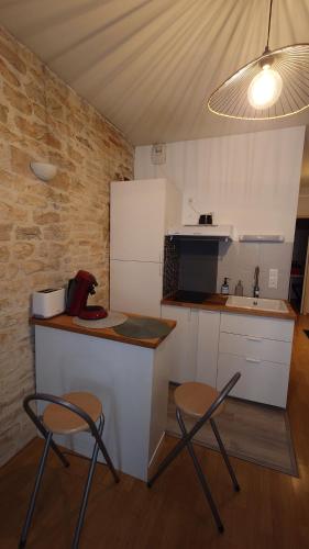 une cuisine avec deux chaises et un comptoir avec un réfrigérateur dans l'établissement Le Clos des Perrières, à Dijon