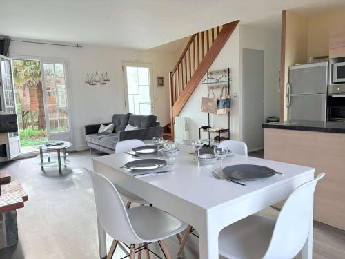 une table blanche et des chaises dans un salon dans l'établissement Maison calme avec jardin et Wifi, proche plages Côte de Granit Rose - FR-1-542-64, à Perros-Guirec