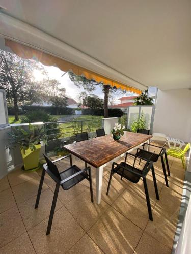 une table et des chaises dans une pièce avec une grande fenêtre dans l'établissement Le Nid du Betey T3, 2CHB, 400m de la plage, à Andernos-les-Bains