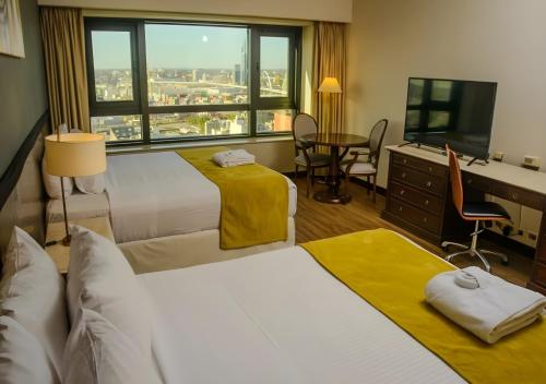 a hotel room with two beds and a desk at Radisson Montevideo Victoria Plaza Hotel in Montevideo