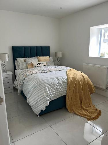 a bed with a blue headboard in a bedroom at The Bleach Green Cottage in Drumahoe