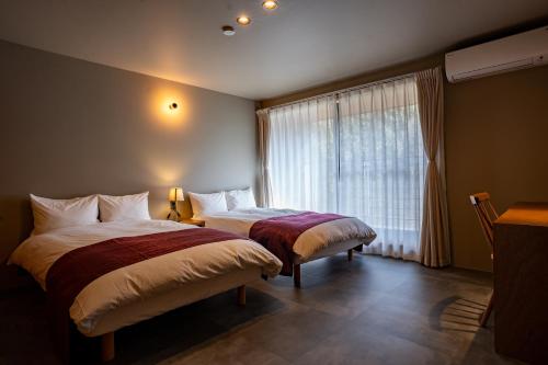 a bedroom with two beds and a window at HARUKA KANATA 森のヴィラ in Minamiboso