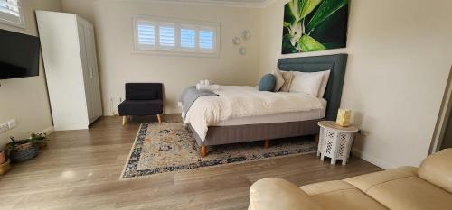 a bedroom with a bed and a chair and a couch at Modern Studio 10mins walk to Wollongong Hospital & Train Station with Parking in Wollongong