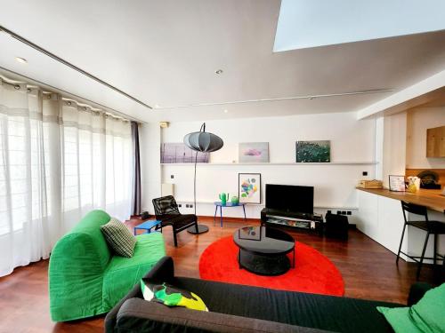 a living room with a green couch and a red rug at Maison centre ville proche plage Wifi in Concarneau