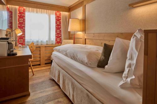 a hotel room with a large bed and a desk at The Glacier Hotel - ex Eurotel Victoria - in Les Diablerets