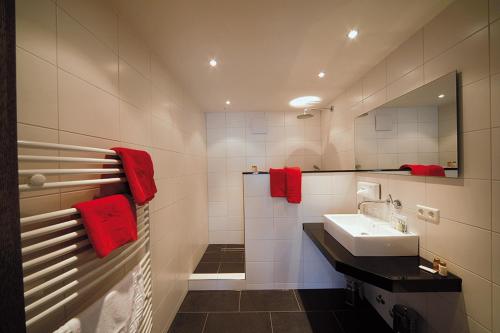 a bathroom with a sink and a mirror and red towels at Stern in Albershausen