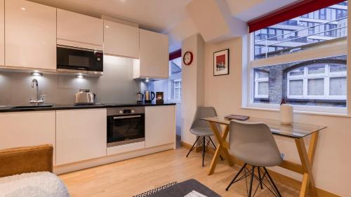 a kitchen and dining room with a table and chairs at Barbican Serviced Apartments by LovelyStay in London