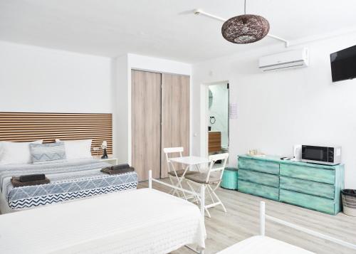 a white bedroom with a bed and a desk at Taah Billa Guest House in Tavira