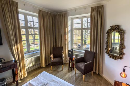 a bedroom with a bed and two chairs and windows at Kasteel Pietersheim Maastricht - Lanaken in Lanaken
