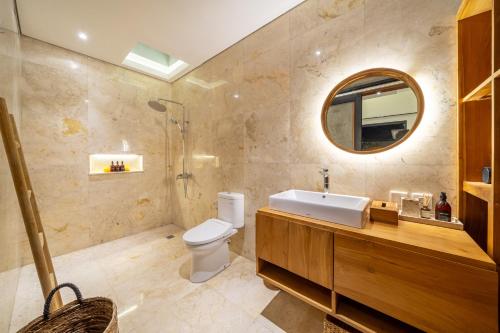 a bathroom with a sink and a toilet and a mirror at Lecatica - Brand New 2BDR Paradise Villa with Expansive Pool - Your Dream Retreat in Canggu! in Seminyak