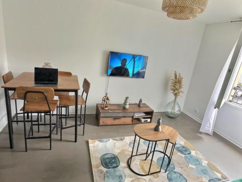 - un salon avec une table, des chaises et un ordinateur portable dans l'établissement Confort Exotique Idéal Pour Les Familles Et Les Groupes, à Persan