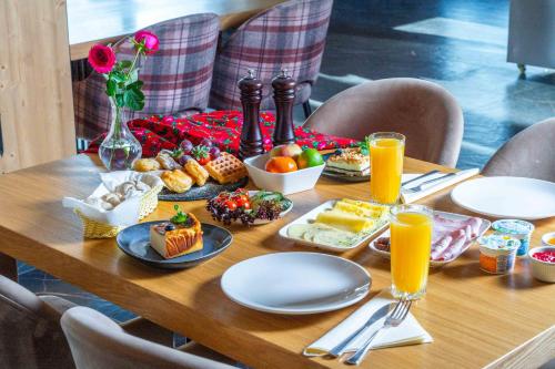 a table with breakfast foods and orange juice on it at Hotel Maria & Spa in Szczawnica