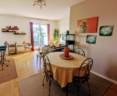 un salon avec une table avec des chaises et un canapé dans l'établissement Refuge du pilote tout équipé au calme avec balcon, à Dax