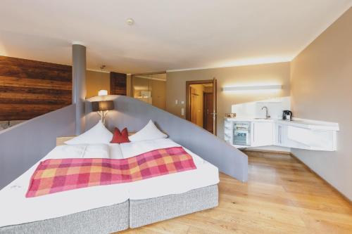 a bedroom with a large bed and a kitchen at Auhof Wirtshaus & Suiten in Kaprun