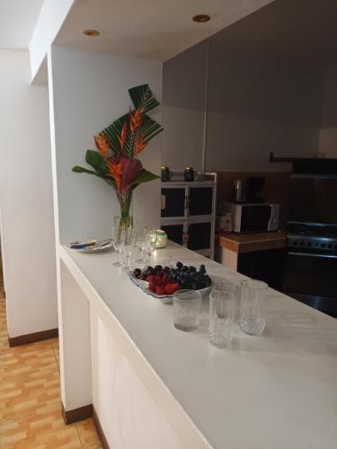 a kitchen counter with glasses and a bowl of fruit at St Michel complex in Grand Gaube