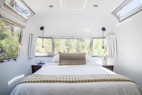a bedroom with a bed with white sheets and windows at AutoCamp Sequoia in Three Rivers