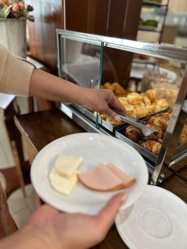 a person holding a plate with cheese and other food at Lagoa Parque Hotel in Lagoa Vermelha