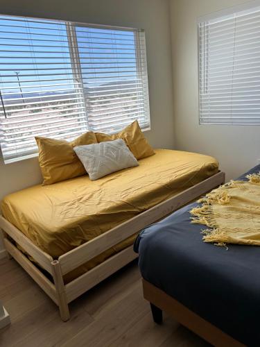 a bedroom with two twin beds and a window at Serene Modern Home Backdoor with great WiFi, games, movies, patio seating and bbq Easy Access to North Joshua Tree National Park in 10 minutes in Twentynine Palms