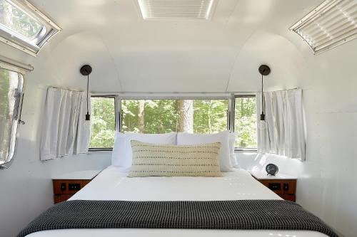 a bedroom with a white bed with windows at AutoCamp Sequoia in Three Rivers