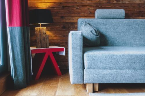 a blue chair sitting next to a side table with a lamp at Auhof Wirtshaus & Suiten in Kaprun