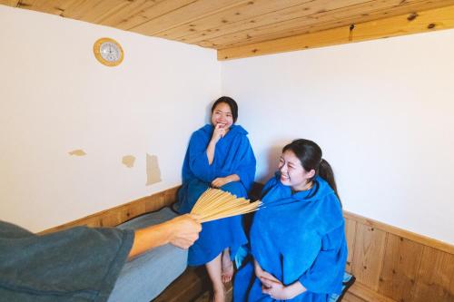 two women in blue robes standing in a room at 交流型ゲストハウス伊良部ジャーニーインIrabu Joureny INN#毎日みんなで夕食会#ゲストさんは20-30代が中心#海徒歩1分#空港車で5分#本格フィンランドサウナ付き#海と星と夕日が見える屋上あり in Miyako-jima