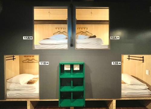 a room with three bunk beds and a green box at Yoroi Asakusa Hotel in Tokyo