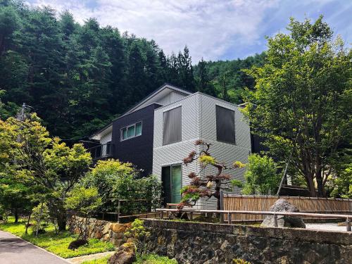 a house on a hill with trees in the background at 山城屋リゾート in Aoki