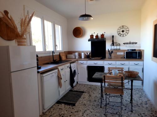 une cuisine avec des appareils blancs et une table avec des chaises dans l'établissement Villa les 4 vents, à Arles