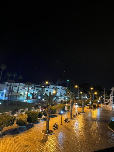 a parking lot with palm trees and lights at night at Bungalow avec une vue panoramique in Sousse