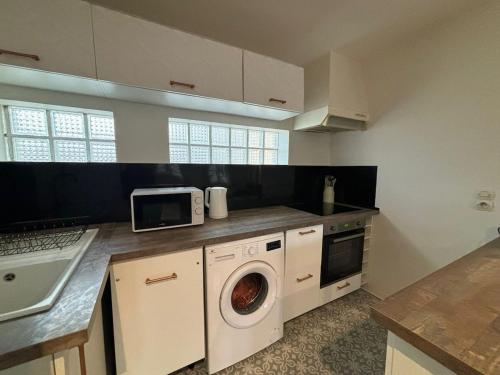 a kitchen with a washing machine and a microwave at Charmant T3 lumineux & cosy in Pomponne