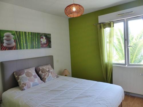 une chambre avec un lit aux murs verts et une fenêtre dans l'établissement Le Brigantin, villa mitoyenne de 68m2 avec terrasse, jardinet et petit garage, à Capbreton
