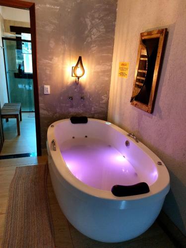 a large white bath tub in a room with a light at Casa da Prainha Lapinha da Serra in Santana do Riacho