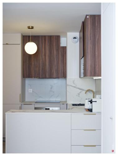une cuisine avec des comptoirs blancs et des armoires en bois dans l'établissement Chic appart 3 pièces avec Parking et Terrasse à 35min de Paris, à Romainville