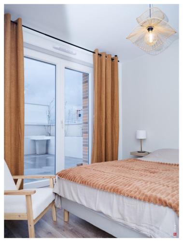une chambre avec un lit et une porte coulissante en verre dans l'établissement Chic appart 3 pièces avec Parking et Terrasse à 35min de Paris, à Romainville