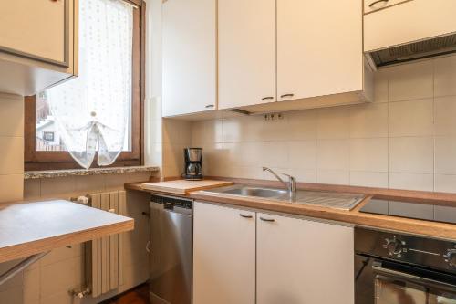 a kitchen with white cabinets and a sink and a window at Valley Hideaway with private garden near Como lake in Taceno