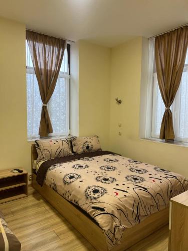 a bedroom with a bed and two windows at СТОНЕЛ in Veliko Tŭrnovo