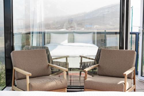 two chairs and a table in a room with a bed at Zvezdnaya Eco-Hotel in Almaty