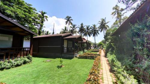 a house with a grass yard next to a building at Golden Sands Resort, Morjim in Morjim