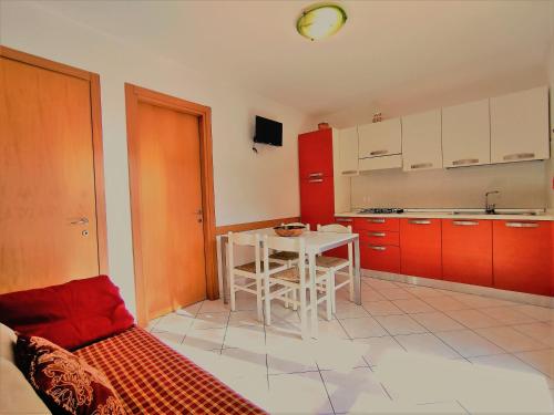 a kitchen with a white table and red cabinets at RESIDENCE El Patio C-4 in Rosolina Mare
