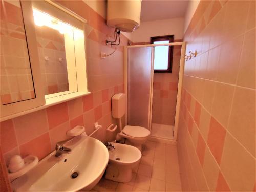 a bathroom with a sink and a toilet and a mirror at RESIDENCE El Patio C-4 in Rosolina Mare