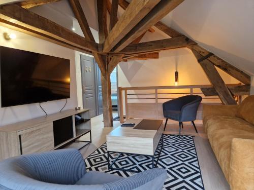 un soggiorno con un divano e una TV di Gite spa atypique, Vosges, chez Bubu, école rénovée bain nordique et nature a Vecoux