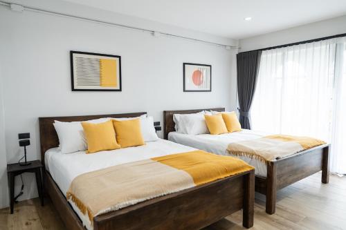 a bedroom with two beds with yellow pillows at Knox Hatyai just 10 steps to Greenway Night Market in Sathani Khlong Rian